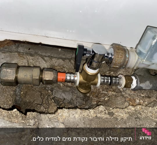 צנרת מתכת עם ברזים ומחברים על קיר בטון